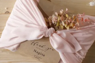 風呂敷の結び目にアクセントの花が飾られたつつみ体重米